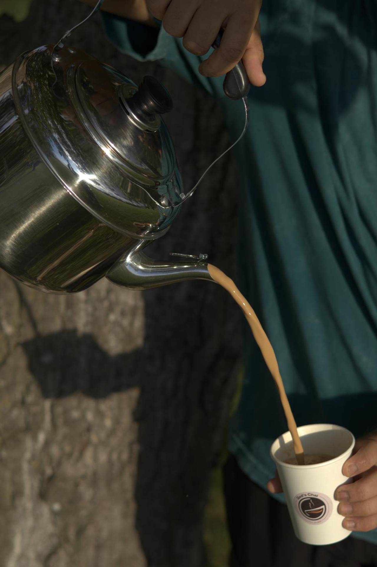Masala chai being poured from a steel kettle